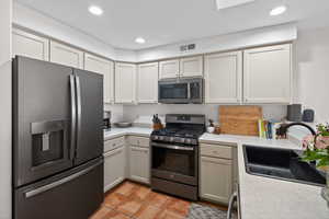 Kitchen with stainless steel appliances, light countertops, recessed lighting, light tile patterned floors, and white cabinetry