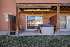 Property entrance with stucco siding, a patio, and a hot tub