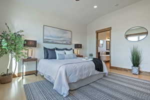Bedroom with wood finished floors, lofted ceiling, ensuite bath, and recessed lighting