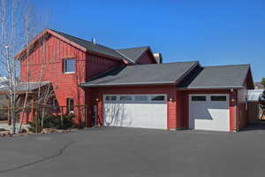 View of property exterior with an attached garage, roof with shingles, driveway, and a chimney