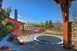 View of yard with a trampoline and a deck with mountain view