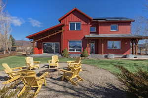 Back of house featuring solar panels, a yard, a patio area, and a mountain view