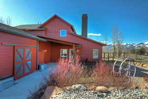Back of house with a chimney, a mountain view, board and batten siding, and a patio area