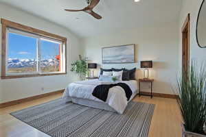 Bedroom featuring light wood finished floors, ceiling fan, a mountain view, and lofted ceiling