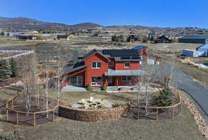 Back of property featuring roof mounted solar panels, a patio, a mountain view, and board and batten siding