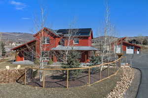 View of front of house with solar panels, a porch, an outbuilding, and a mountain view