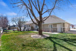 Back of property with stone siding, stucco siding, and roof with shingles