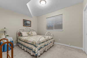 Bedroom featuring light colored carpet and a textured ceiling