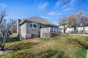 Back of house with stucco siding, stone siding, a chimney, and a wooden deck