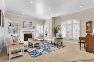 Living area with light carpet, a glass covered fireplace, crown molding, and recessed lighting