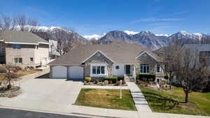 View of front of house featuring stone siding, a garage, a mountain view, driveway, and a front yard