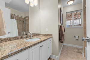 Full bathroom featuring vanity, curtained shower, and light tile patterned flooring