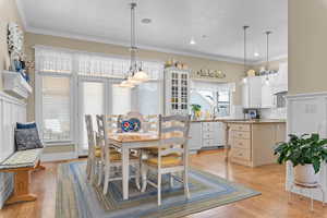 Dining space with crown molding and light wood finished floors