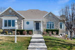 View of front of home featuring stone siding, a front yard, board and batten siding, and a shingled roof