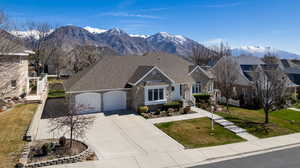 View of front of home featuring stone siding, a garage, driveway, a front yard, and a mountain view