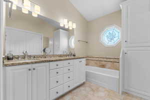 Full bath featuring double vanity, a bath, and light tile patterned floors