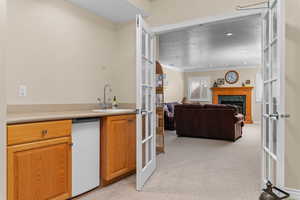 Kitchen with french doors, a fireplace, light colored carpet, open floor plan, and a textured ceiling