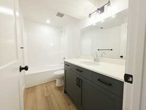 Bathroom featuring light wood finished floors, vanity, and washtub / shower combination