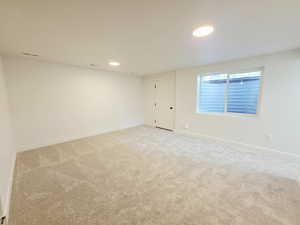 Empty room with light carpet and recessed lighting