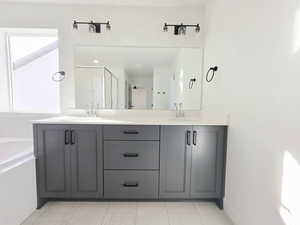 Full bathroom featuring double vanity, a bath, and a stall shower