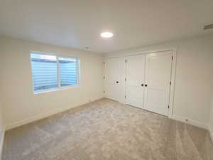 Unfurnished bedroom with a closet and light colored carpet