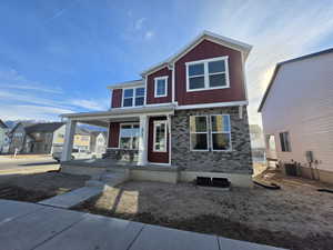 View of front of house featuring covered porch, a residential view, brick siding, and board and batten siding