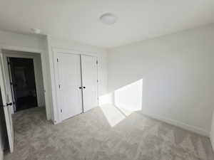 Unfurnished bedroom featuring light colored carpet and a closet