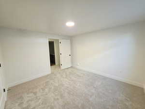 Unfurnished room featuring baseboards and light carpet