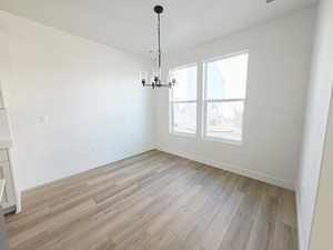 Unfurnished dining area featuring light wood finished floors and suspended lighting