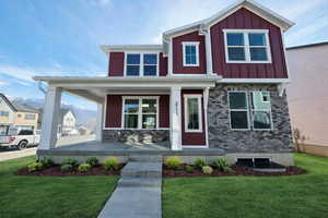 Craftsman-style home featuring covered porch, a front lawn, board and batten siding, and a mountain view