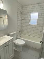 Bathroom with a textured wall, vanity, bathtub / shower combination, and light tile patterned floors
