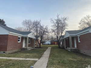 View of property exterior with a yard, crawl space, brick siding, and a shingled roof