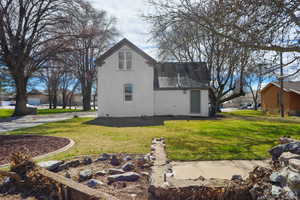 View of side of property featuring a lawn, a shingled roof, and stucco siding