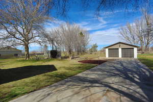 View of green lawn featuring an outbuilding and a detached garage