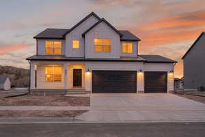 Modern inspired farmhouse with a porch, driveway, board and batten siding, an attached garage, and a metal roof