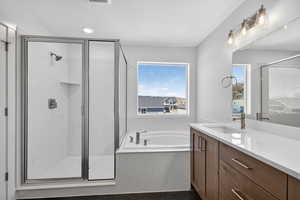 Full bath with vanity, a marble finish shower, and a garden tub