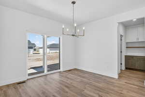 Unfurnished dining area featuring light wood finished floors and hanging lights