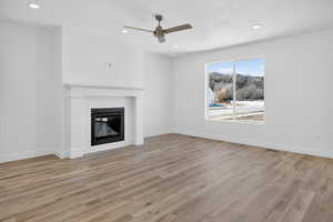 Unfurnished living room with ceiling fan, light wood-style floors, recessed lighting, and a tiled fireplace