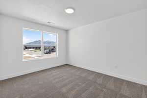 Spare room featuring dark colored carpet and a mountain view