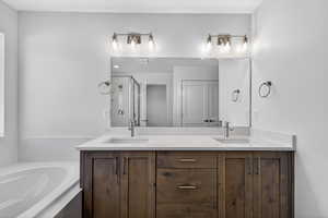 Full bathroom with double vanity, a garden tub, and a shower stall