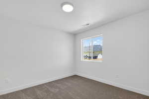 Unfurnished room featuring a mountain view and dark colored carpet