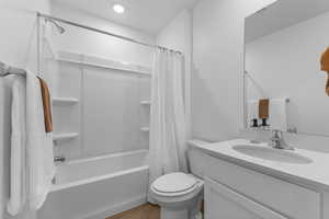 Full bathroom with vanity, shower / bathtub combination with curtain, and dark wood-style flooring
