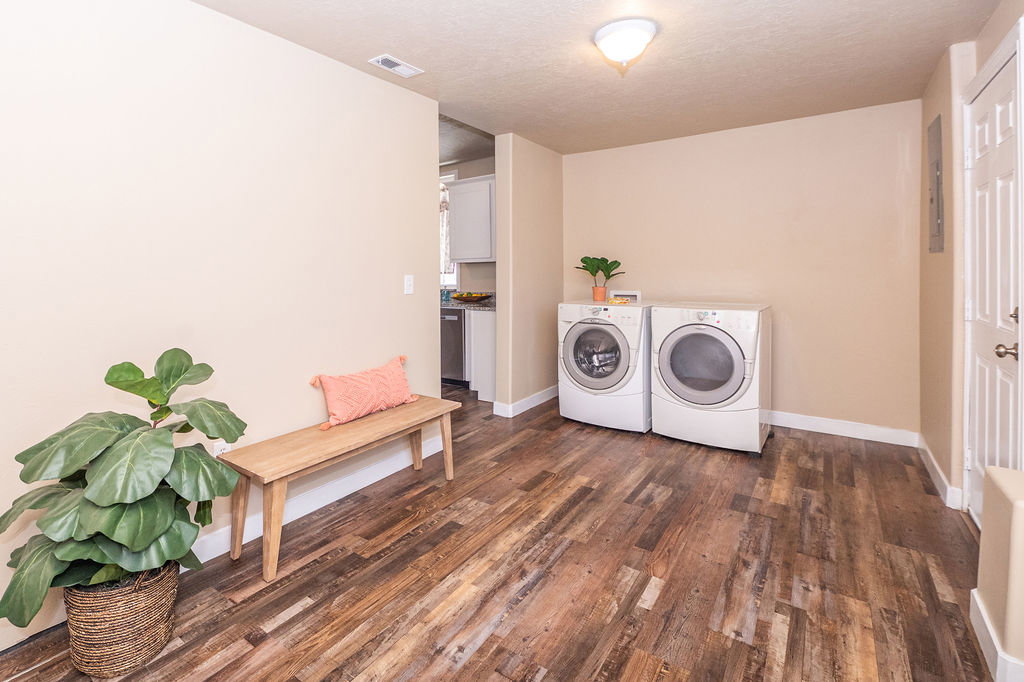Laundry area with dark wood-style flooring, washing machine and dryer, a textured ceiling, and electric panel