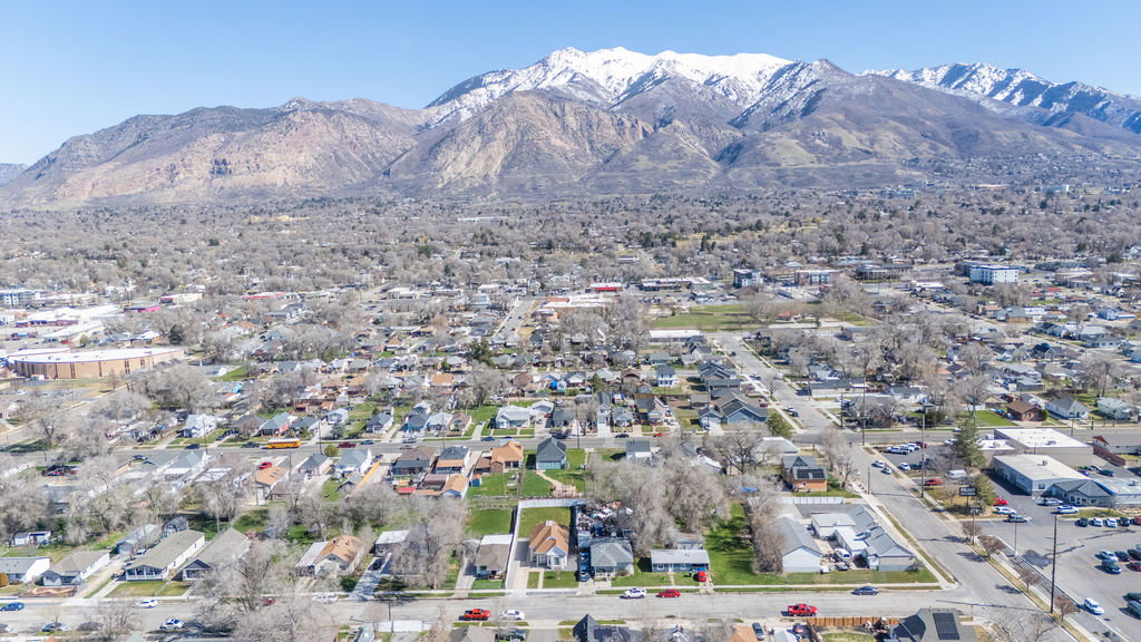 Aerial view of property and surrounding area featuring a mountainous background and nearby suburban area