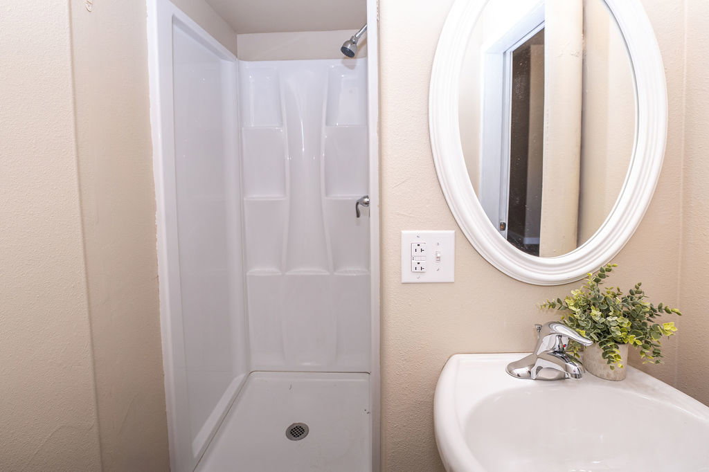 Full bath featuring a shower stall and a textured wall