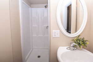 Full bath featuring a shower stall and a textured wall