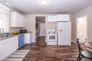 Kitchen featuring white appliances, white cabinets, dark wood-style floors, dark stone counters, and a textured ceiling