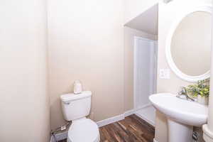 Half bath with toilet and dark wood-style floors