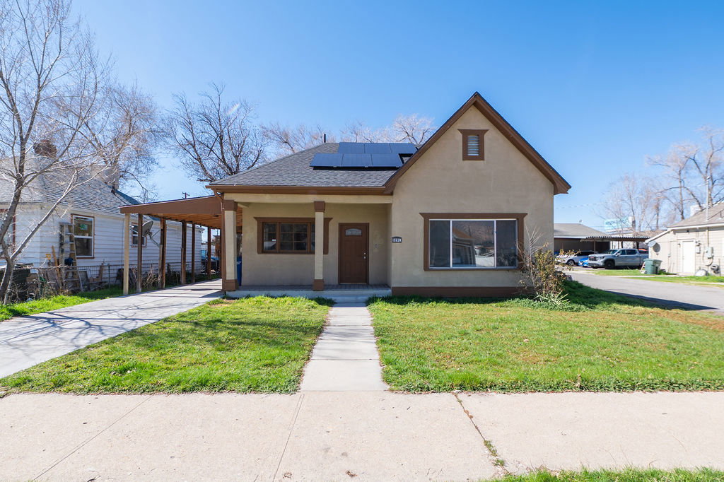 View of front of house with a porch, a carport, roof mounted solar panels, stucco siding, and concrete driveway