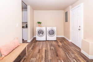 Laundry area featuring dark wood-style floors, electric panel, and washer and clothes dryer